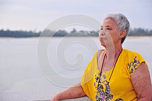 Old asian lady relaxing to sea view