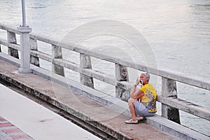 Old asian lady resting on concrete bridgeold asian lady resting on concrete bridge