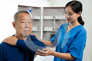 An old Asian man is doing physical therapy with the support of a nurse in the living room by exercising