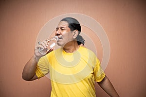 old asian man holding and drinking from unlabelled plastic bottle