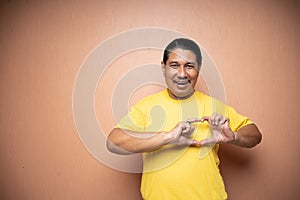 old asian man making heart sign with his finger over his chest