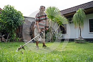 Old asian man mowing his garden