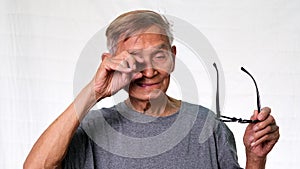 The old Asian man smiled happily showing his missing teeth and holding dentures in his hand. Health and dental care concept