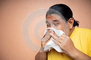 old asian man suffering from flu using tissue to wipe runny nose