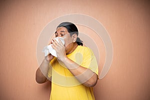 old asian man suffering from flu using tissue to wipe runny nose