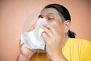 old asian man using tissue to cover sneezing