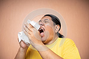 old asian man using tissue to cover sneezing