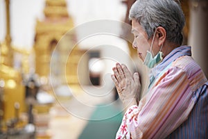 Old asian senior woman traveler tourist praying at buddhist temple