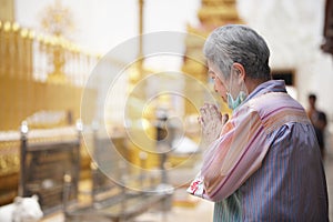 Old asian senior woman traveler tourist praying at buddhist temple