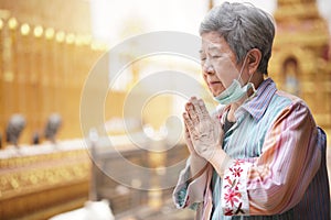 Old asian senior woman traveler tourist praying at buddhist temple