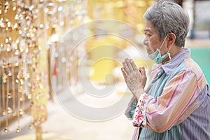 Old asian senior woman traveler tourist praying at buddhist temple