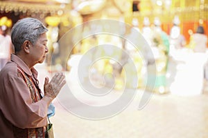 Old asian senior woman traveler tourist praying at buddhist temple