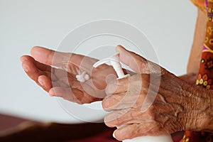 Old Asian Woman hands holding body lotion bottle and using cream for treatment skin in winter time. photo