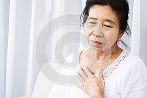 Old Asian woman having problem with shortness of breath, difficult breathing hand touching her chest