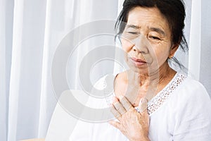 Old Asian woman having problem with shortness of breath, difficult breathing hand touching her chest photo