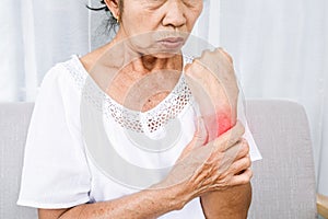 Old Asian woman suffering from wrist pain massaging her numbing pain in hand photo