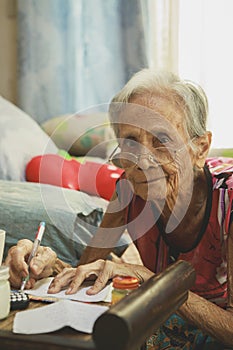 old asian woman writing wording on white paper at home living room