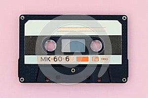 Old audio tape cassette on a pink background. Top view, old technology concept