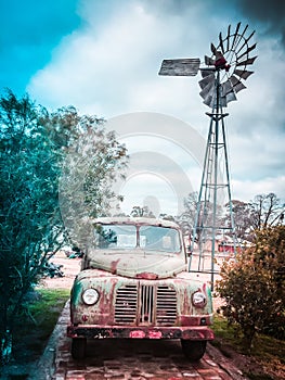 Old Australian outback windmil water pump and vintage rusty vehicle. photo