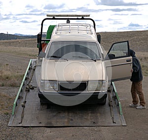 Old automobile being loaded onto a tow truck bed