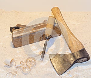 Old ax, plane, chisel and wood shavings on a light background