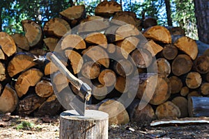 Old axe standing against a piled pieces of firewood