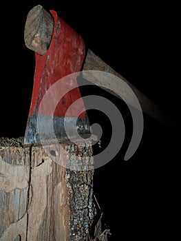 Old axe stuck in log isolated over black