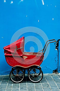 An old baby carriage against a blue wall