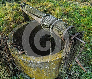 Old backyard well with a flask and a bucket on a cord