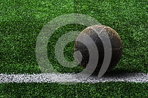 Old ball on artificial grass soccer field background.