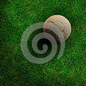 Old ball on green grass soccer field