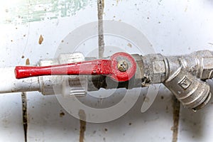 An old ball valve with a red handle to shut off the flow of water. water pipes. ball valve. Concept: repair and replacement of