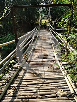 old bamboo suspension bridge passed by motorcyclists