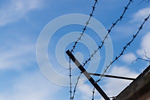 Old barbed wire on the wall. The blue sky is in the background