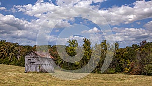 Old barn in a field under a cloudy sky