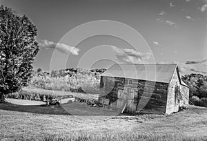 Old barn, garage and car in field black and white
