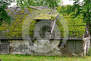 An old barn with a roof covered with moss