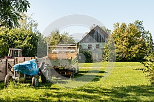 Old barn, tractor and farm machinery in green field