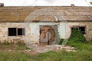 An old barn with a wooden barn door in an agricultural farm. Barn with vibrant green wall and old wooden barn door