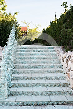 Old baroque stairs, outdoors. Stairs made of stone. Alley in beautiful garden with flowers and trees around.