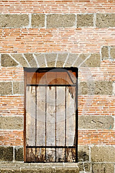 Old Barred Window on a Brick and Stone Wall
