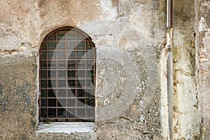 Old, barred window in concrete wall in Rome, Italy