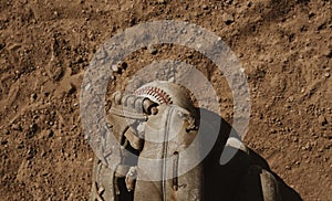 Old baseball glove with ball on field dirt