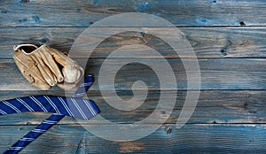 Old baseball glove, ball and neck tie on faded blue wood for happy fathers day concept