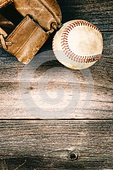 Old baseball and worn mitt on old wood with vintage style