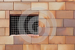 Old basement window with a rusty old prison iron grate with cobwebs on a brickwork wall