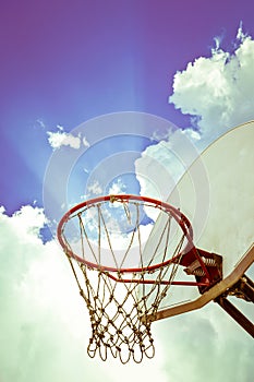 Old basketball board and hoop on blue sky with clouds background