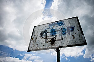 Old basketball court, basket, snatched netting against the sky