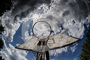 Old basketball court, basket, snatched netting against the sky