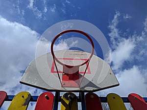 old basketball hoop against a background of blue sky and clouds